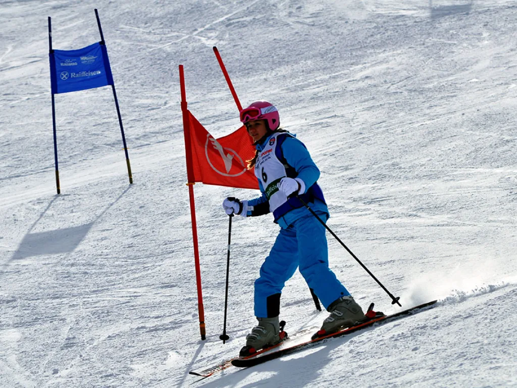 Skifahrerin in blauer Kleidung neben dem roten Tor.